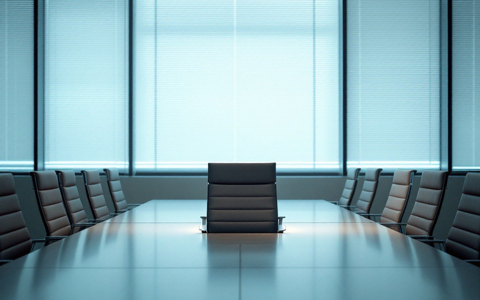 Empty chair facing away in a bare meeting room with half-shut blinds